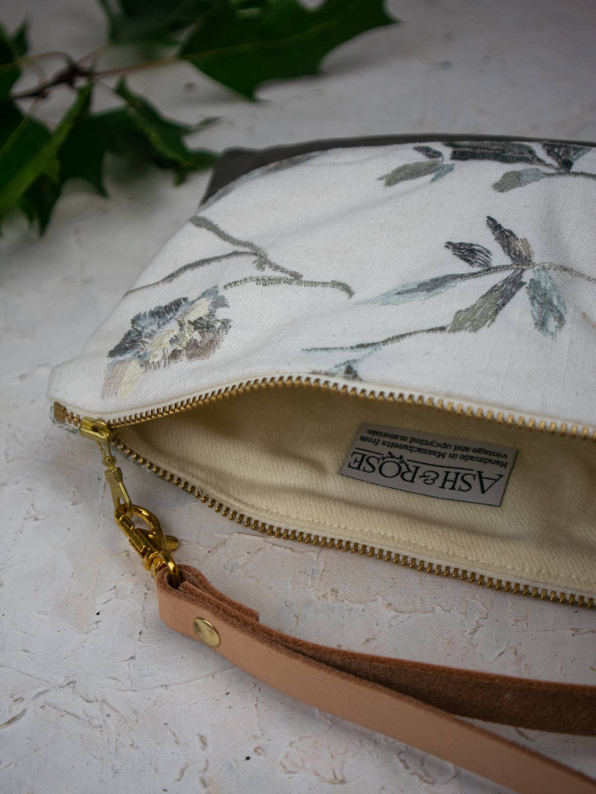 Open Winona Embroidered Linen wristlet showing the Ash & Rose label, handmade in Massachusetts from vintage and upcycled materials, grey floral embroidered exterior