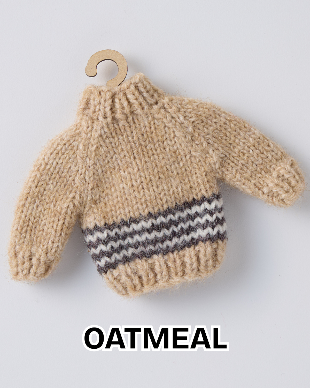 Oatmeal mini knit sweater ornament with a striped hem on a wooden hanger