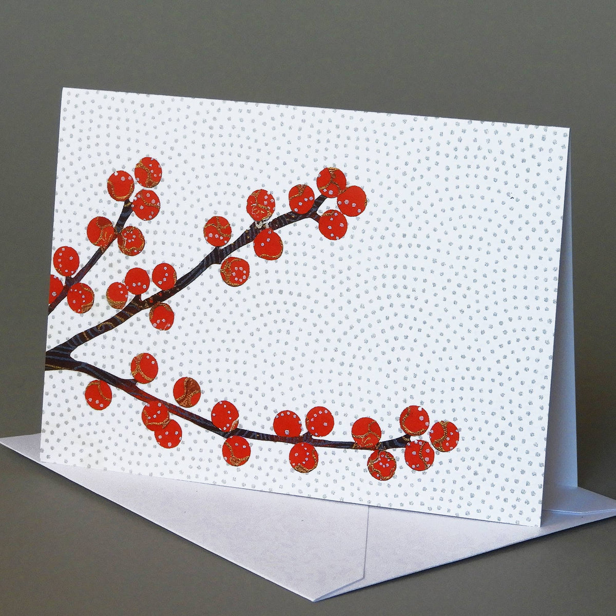 Winterberry notecard of a dark branch with round red berries against a white dotted background, on an envelope