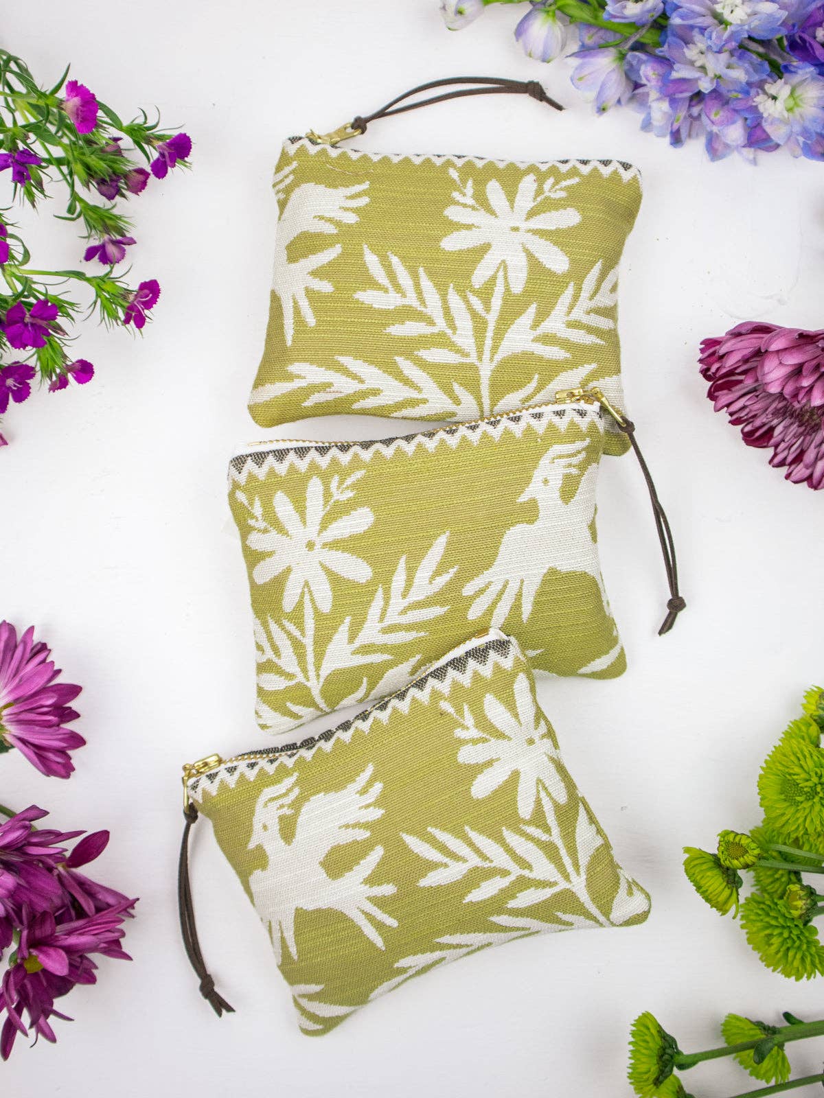Three Folk Life mini pouches in olive green with white daisy, fern, and animal silhouette prints