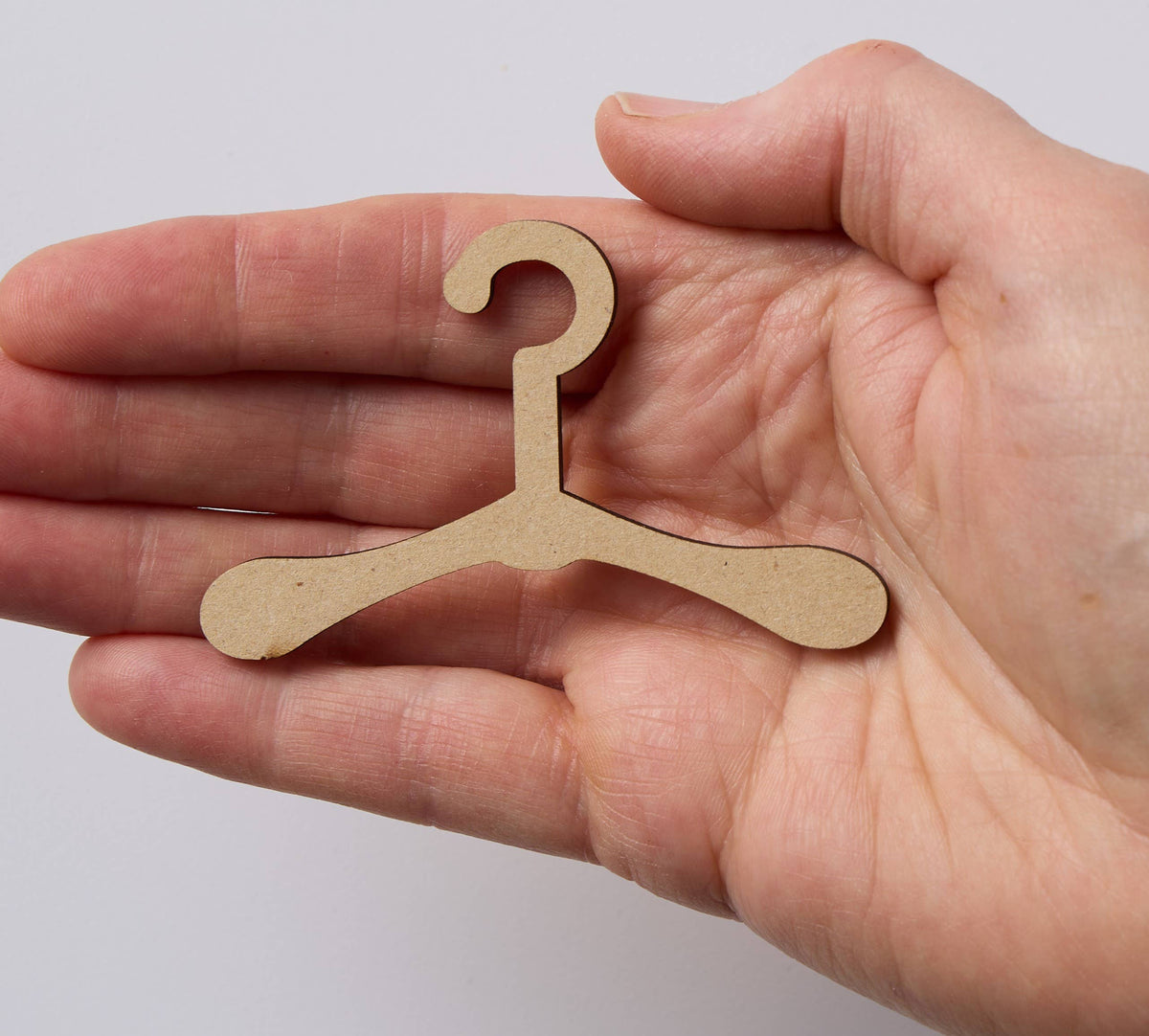 Hand holding the tiny wooden hanger that comes with each ornament