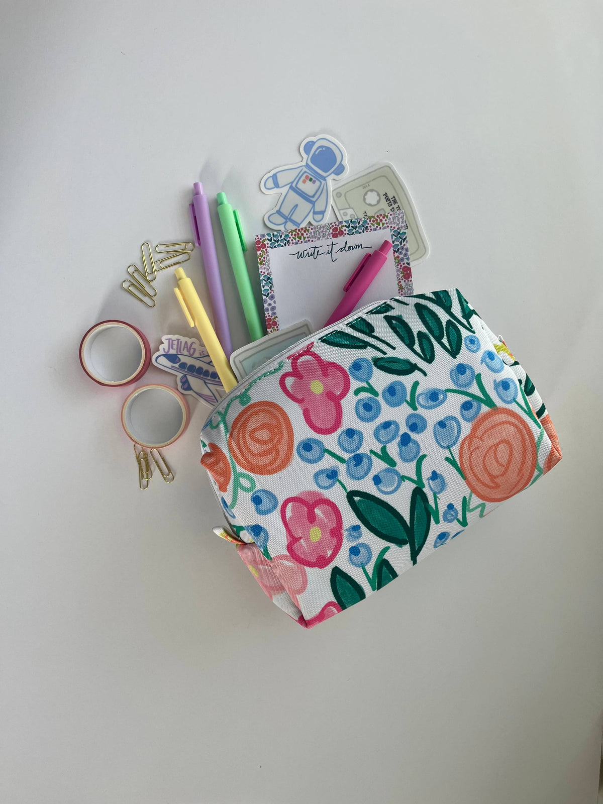 Lauren Floral Zipper Pouch open and overflowing with pastel pens, washi tape, paper clips, stickers, and a write it down notepad