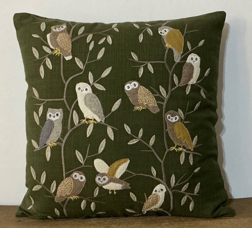 Square olive green pillow with appliqued and embroidered owls in tan, cream and gold wool perched in leafy branches