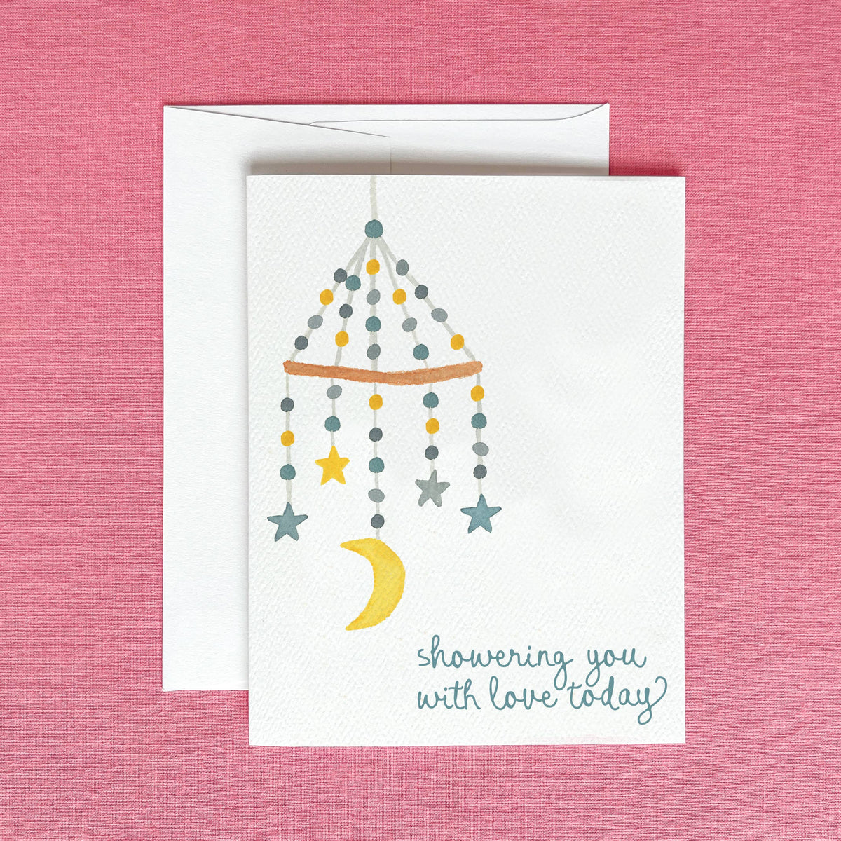 Showering You With Love baby card on a white envelope, over a raspberry pink felt background