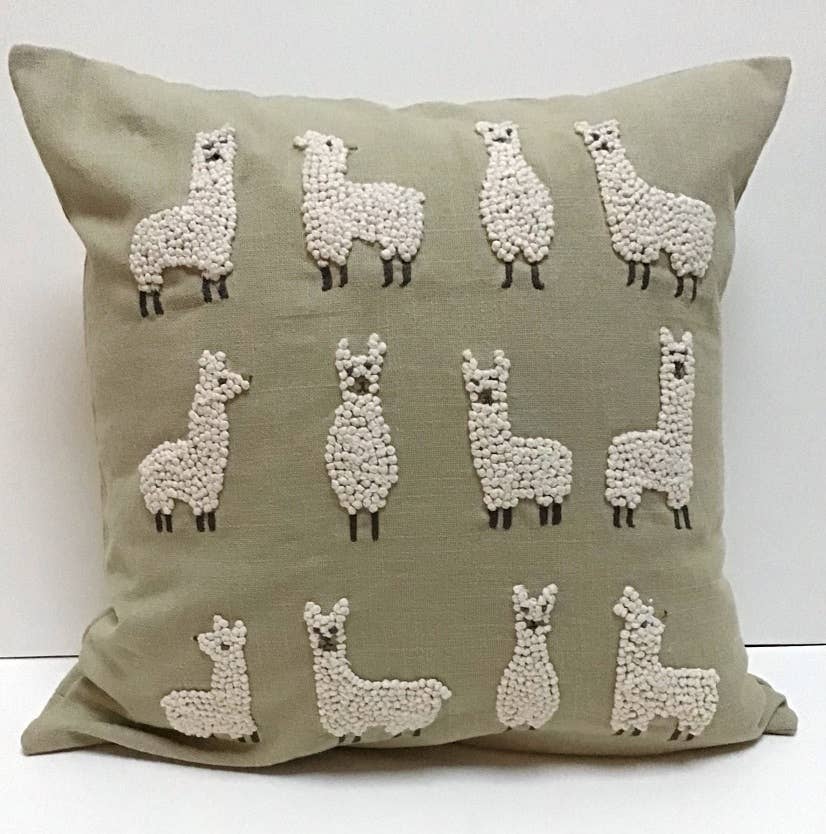 Square sage green cotton pillow embroidered with rows of cream french-knot llamas in different poses