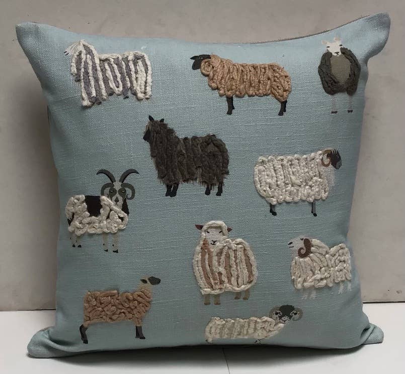 Square pale blue pillow with embroidered and yarn-looped sheep and goats in cream, tan, brown and gray