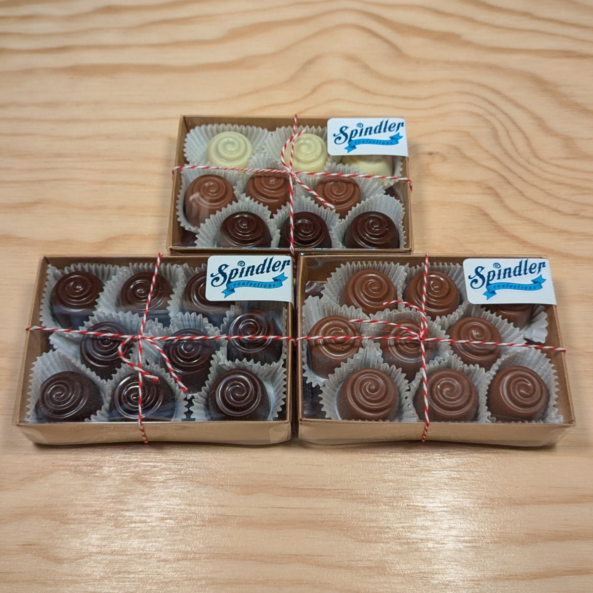 Three boxes of Spindler cherry cordials, one dark, one milk and one assorted with white chocolate, tied with twine