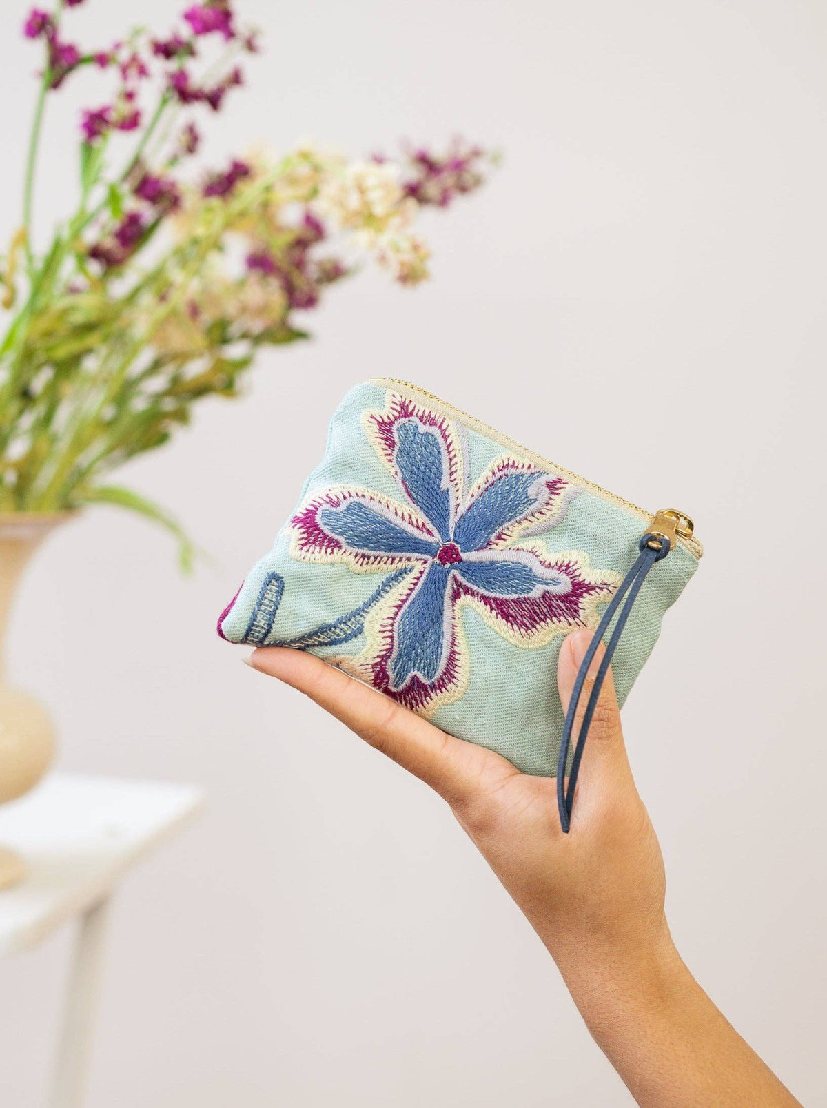 Enchanting Azure embroidered mini pouch, mint green fabric with magenta and blue floral embroidery, near purple wildflowers