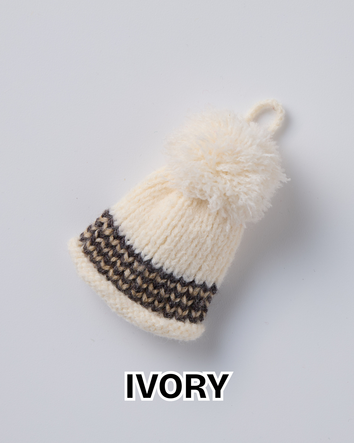 Ivory knit hat ornament with a pom-pom and a brown striped brim