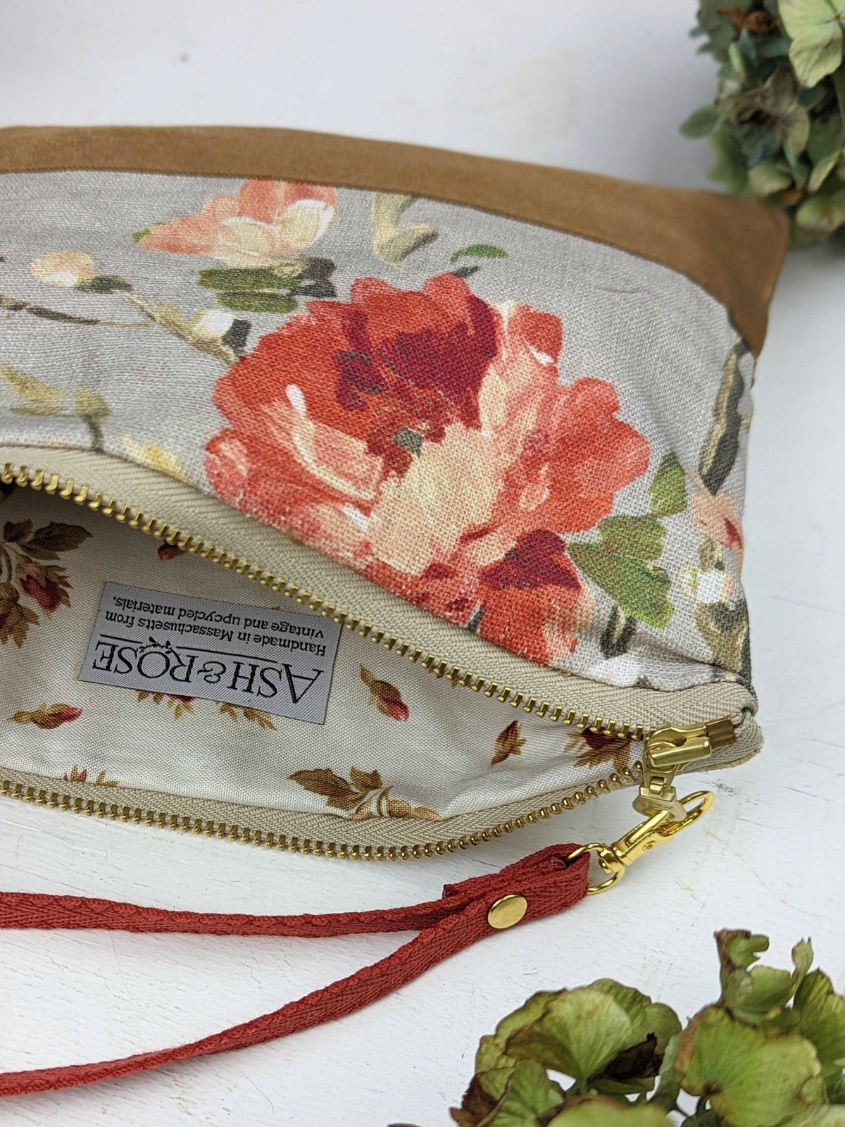 Open Antique Roses wristlet purse showing a floral lining, red and pink rose print exterior, red wrist strap
