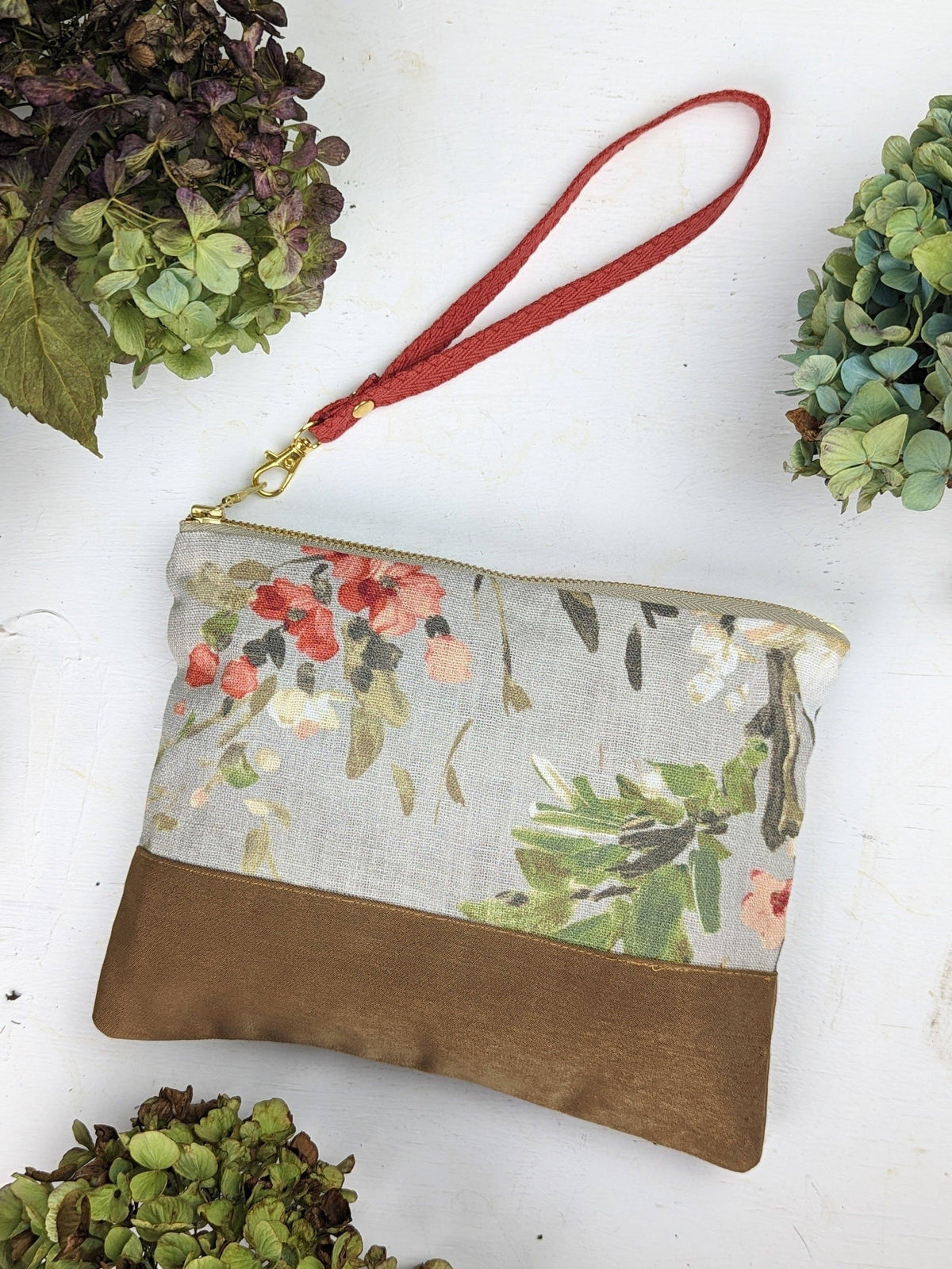 Open Antique Roses wristlet purse showing a pink floral lining and Ash & Rose label, red rose print exterior