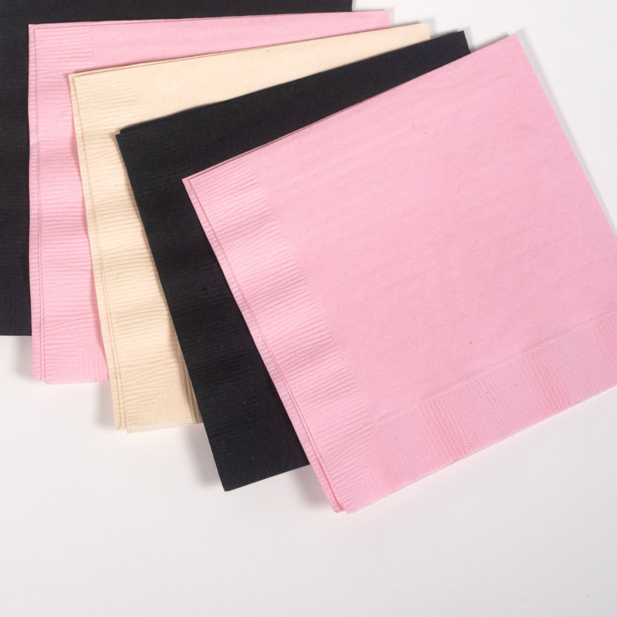 Fanned pink, black and cream paper cocktail napkins on white