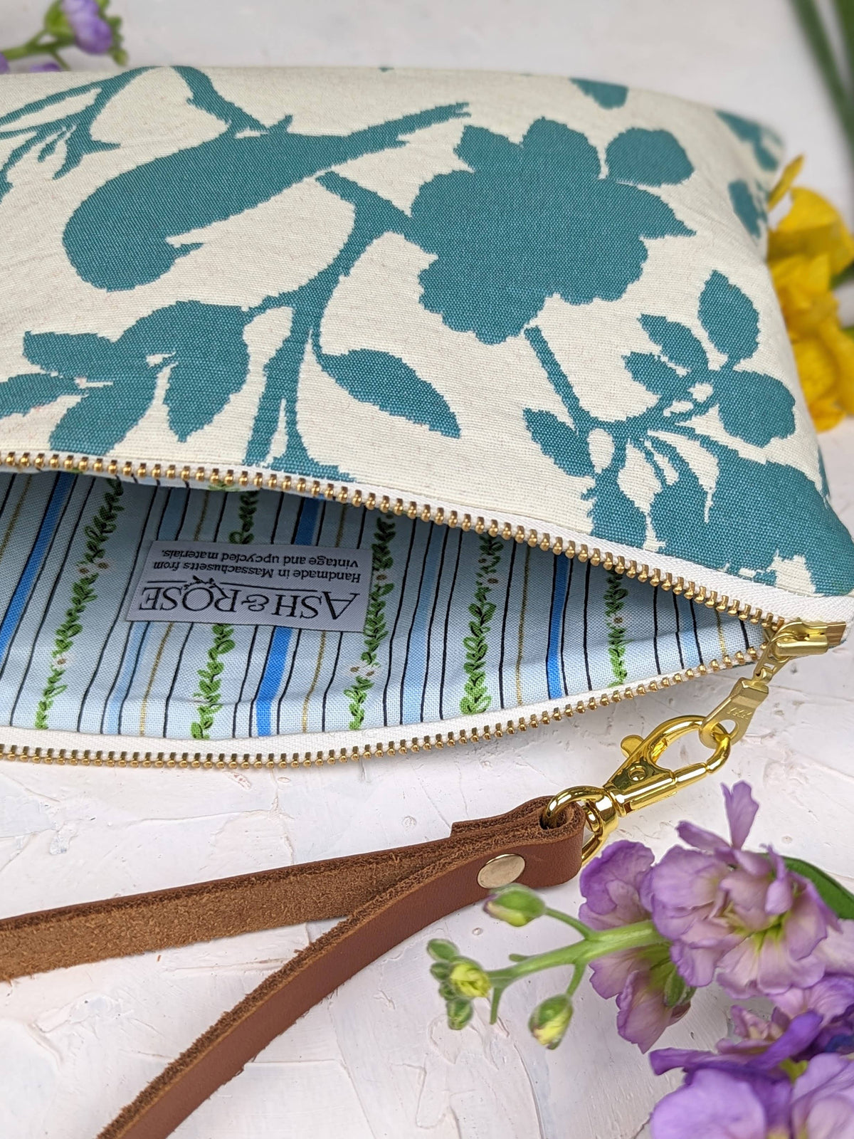 Open Bird Silhouette wristlet purse showing a blue striped lining and the Ash & Rose label, teal bird silhouette exterior
