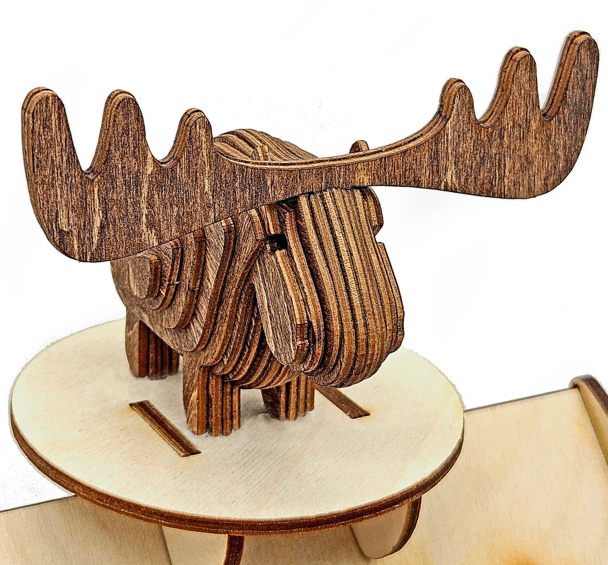 Assembled layered wood moose with wide antlers standing on a round wood stand