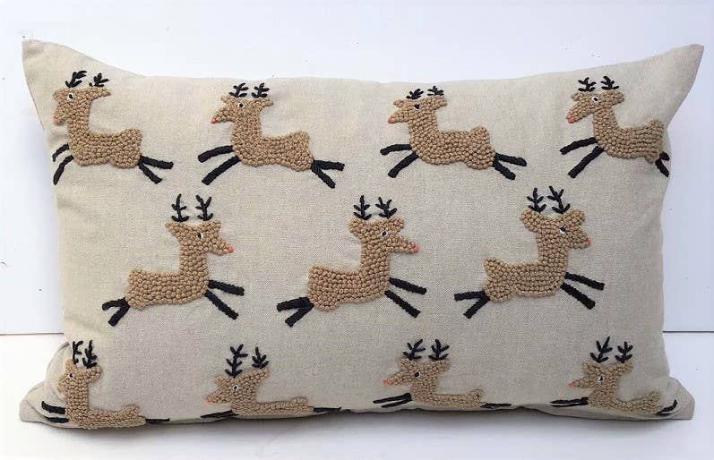Rectangular beige cotton pillow with ten tufted tan knotted reindeer leaping in rows, with black antlers and legs