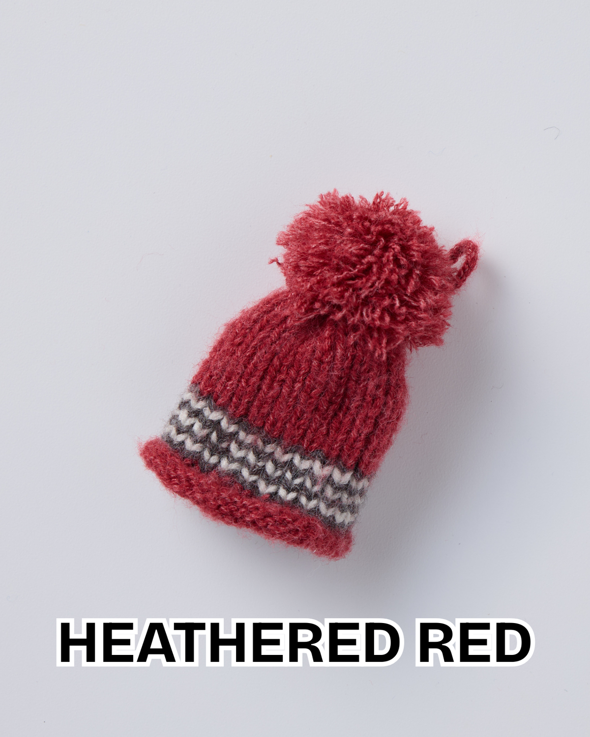 Heathered red knit hat ornament with a pom-pom and a striped brim