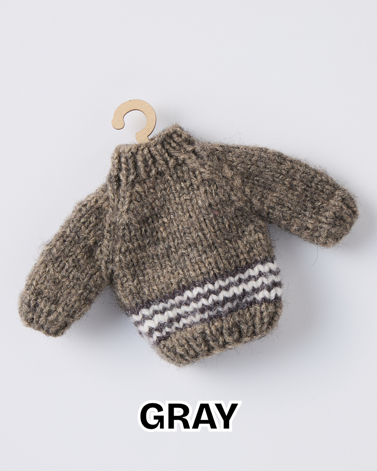 Gray mini knit sweater ornament with a striped hem on a wooden hanger