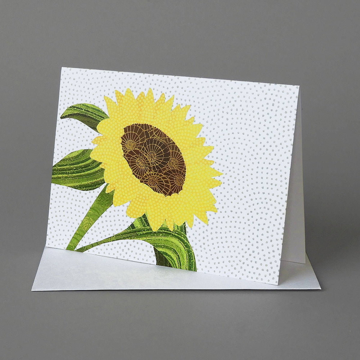 Sunflower notecard of a yellow sunflower with a brown center and green leaves on a white dotted background