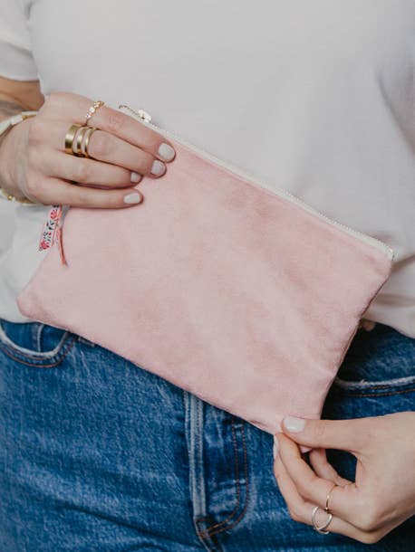 A woman holding the closed blush pink Pink Fleur clutch purse against denim jeans