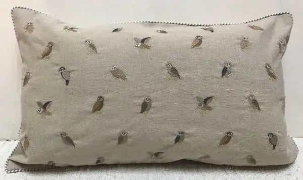 Rectangular oatmeal cotton pillow embroidered with many small owls in gray and brown, with striped piping at the edge