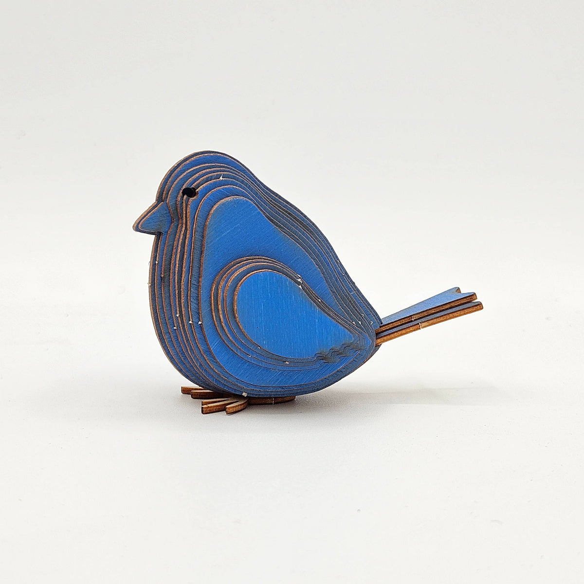 Assembled blue layered wood bird, side view with a fanned tail